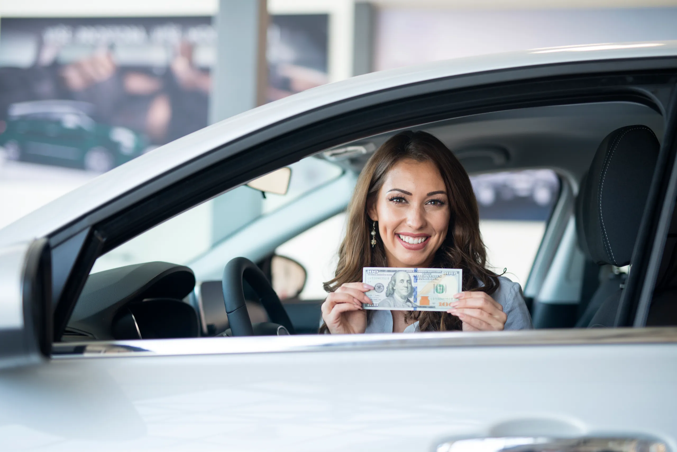 Mujer sonriente en su coche nuevo, apuesta por coches que no pierden valor.