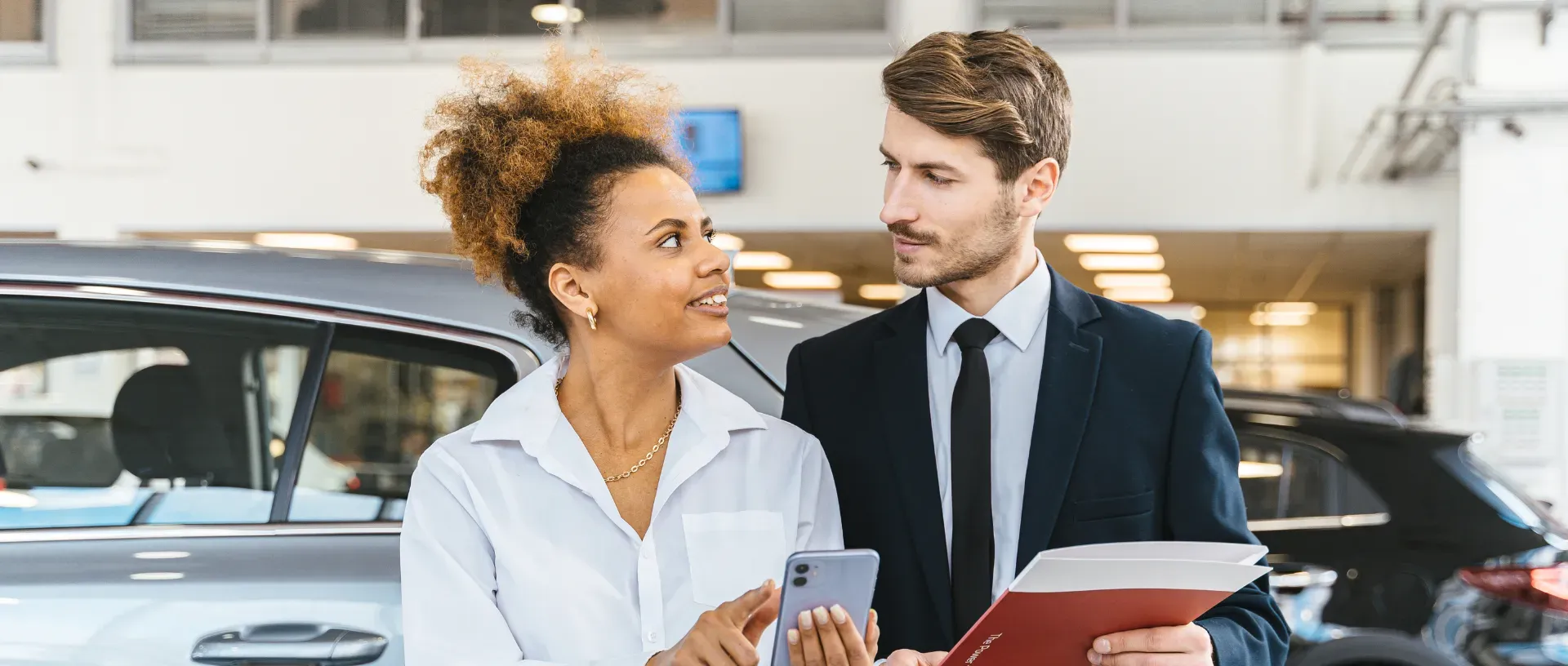 Comercial ayuda a un cliente a tasar el coche antes de venderlo.