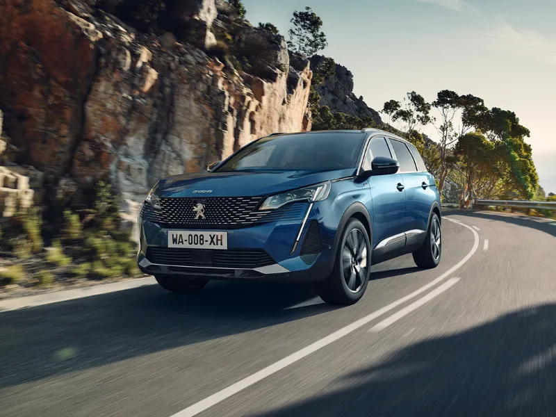 Peugeot 5008 azul circulando por una carretera, ideal entre los coches para 3 hijos.