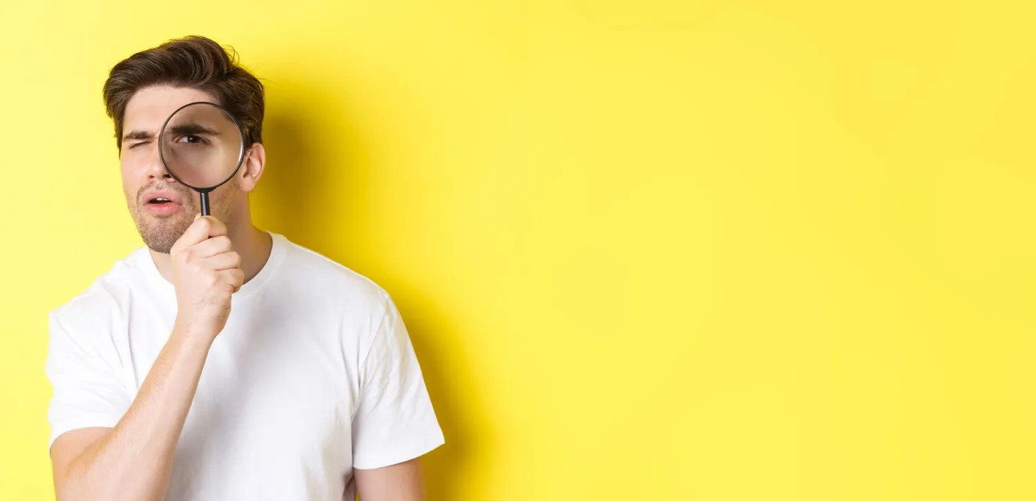 Joven examinando con lupa, ilustrando qué revisar en un coche de segunda mano.