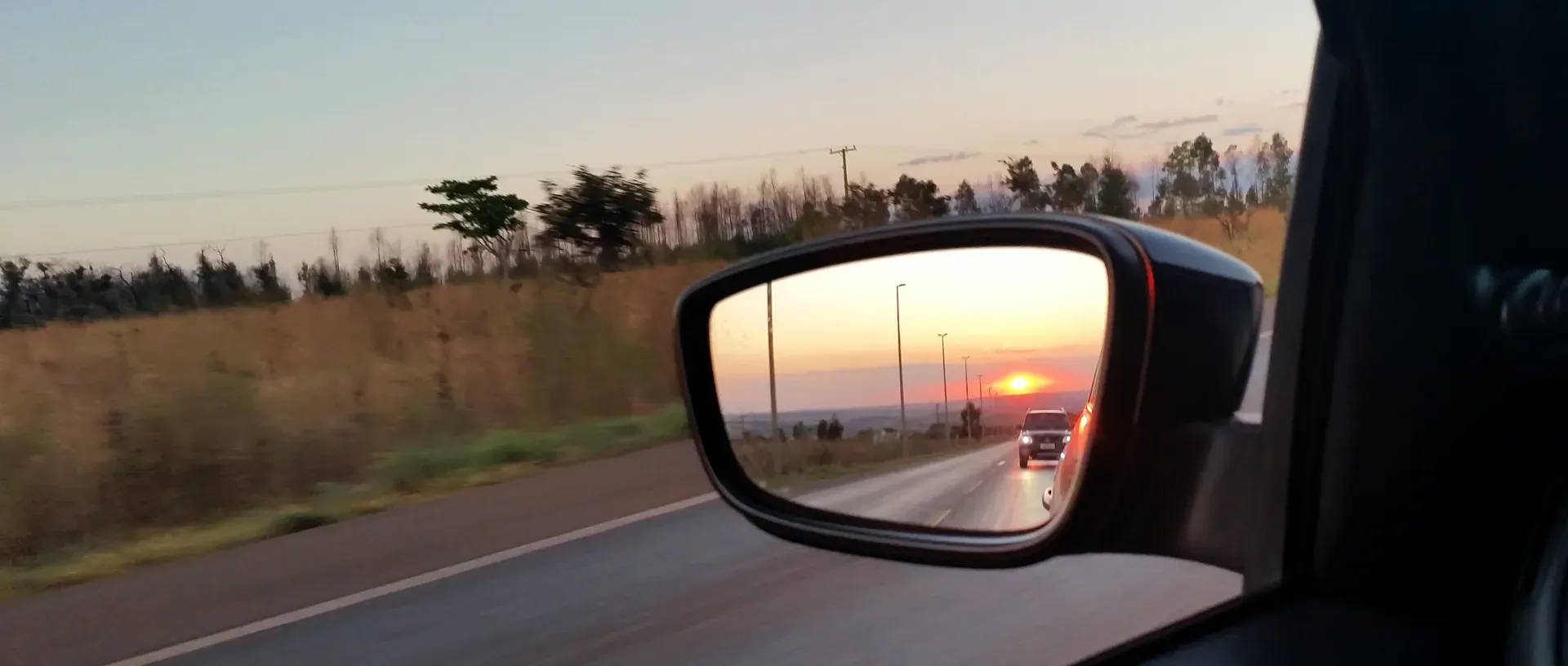 Coche se refleja en el retrovisor. Conducción en carretera al plantearse vender coche sin espejo retrovisor.